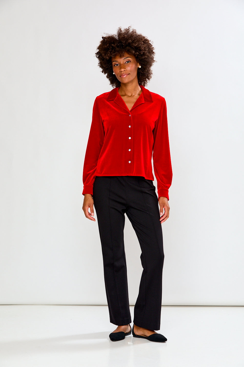 Person wearing a red shirt and black pants on a white background