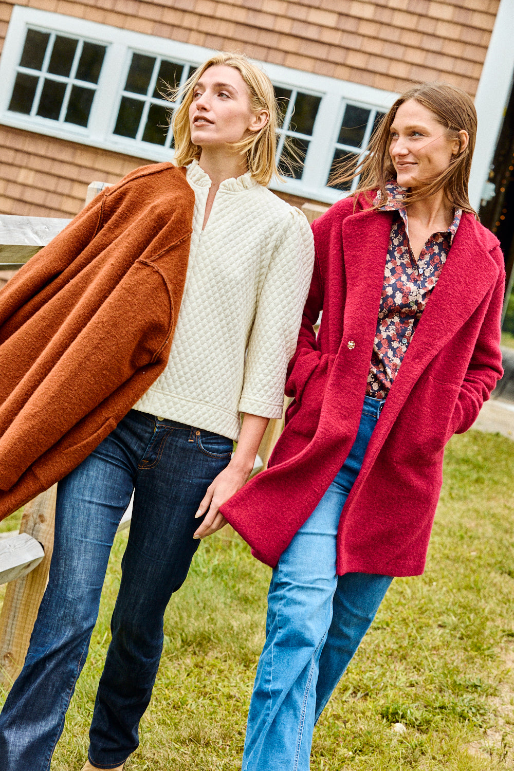 Two women wearing coats standing outdoors in front of a building.