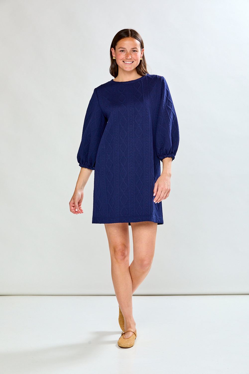 Woman wearing a blue dress with puffed sleeves on a white background