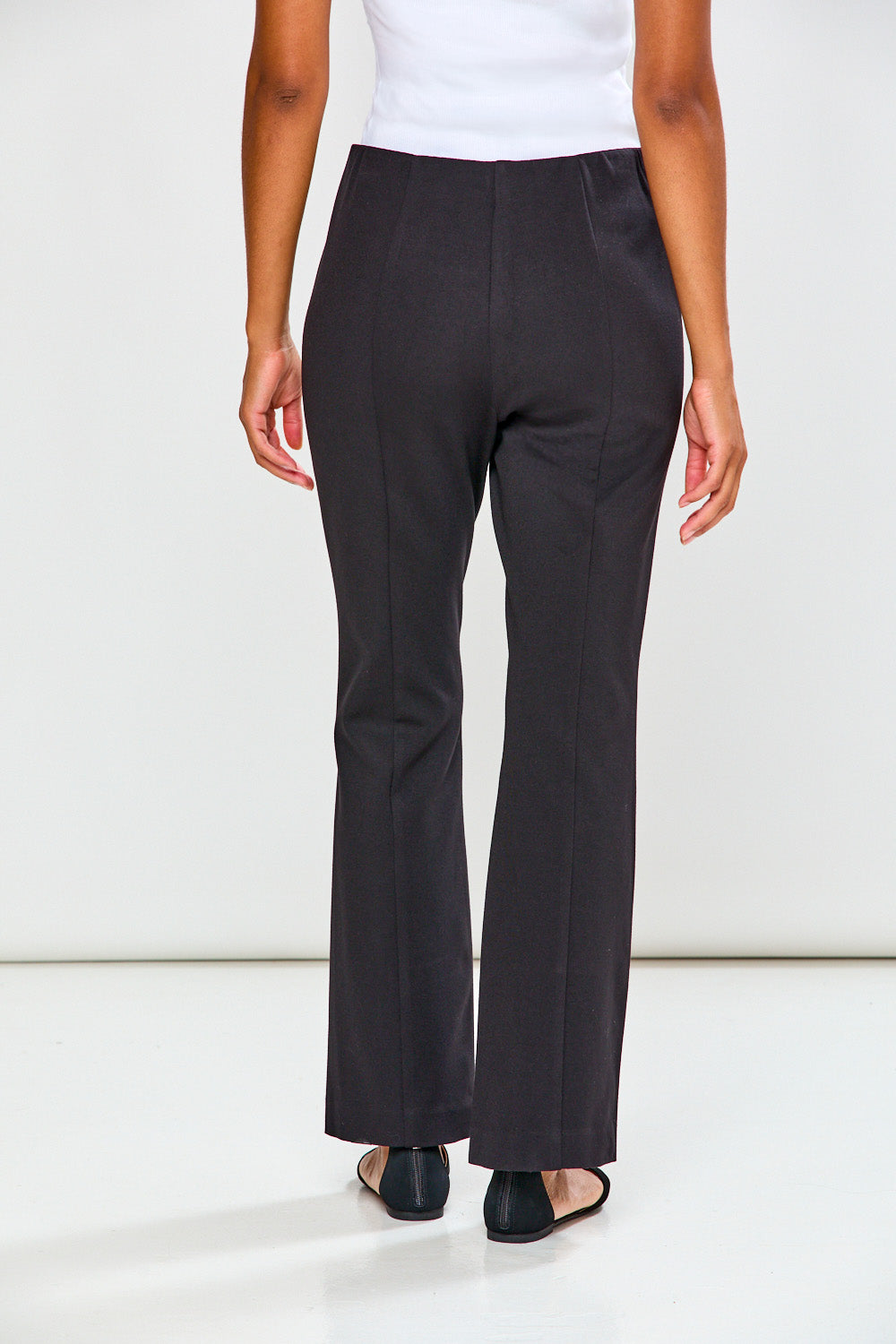 Person wearing black pants and a white top on a white background