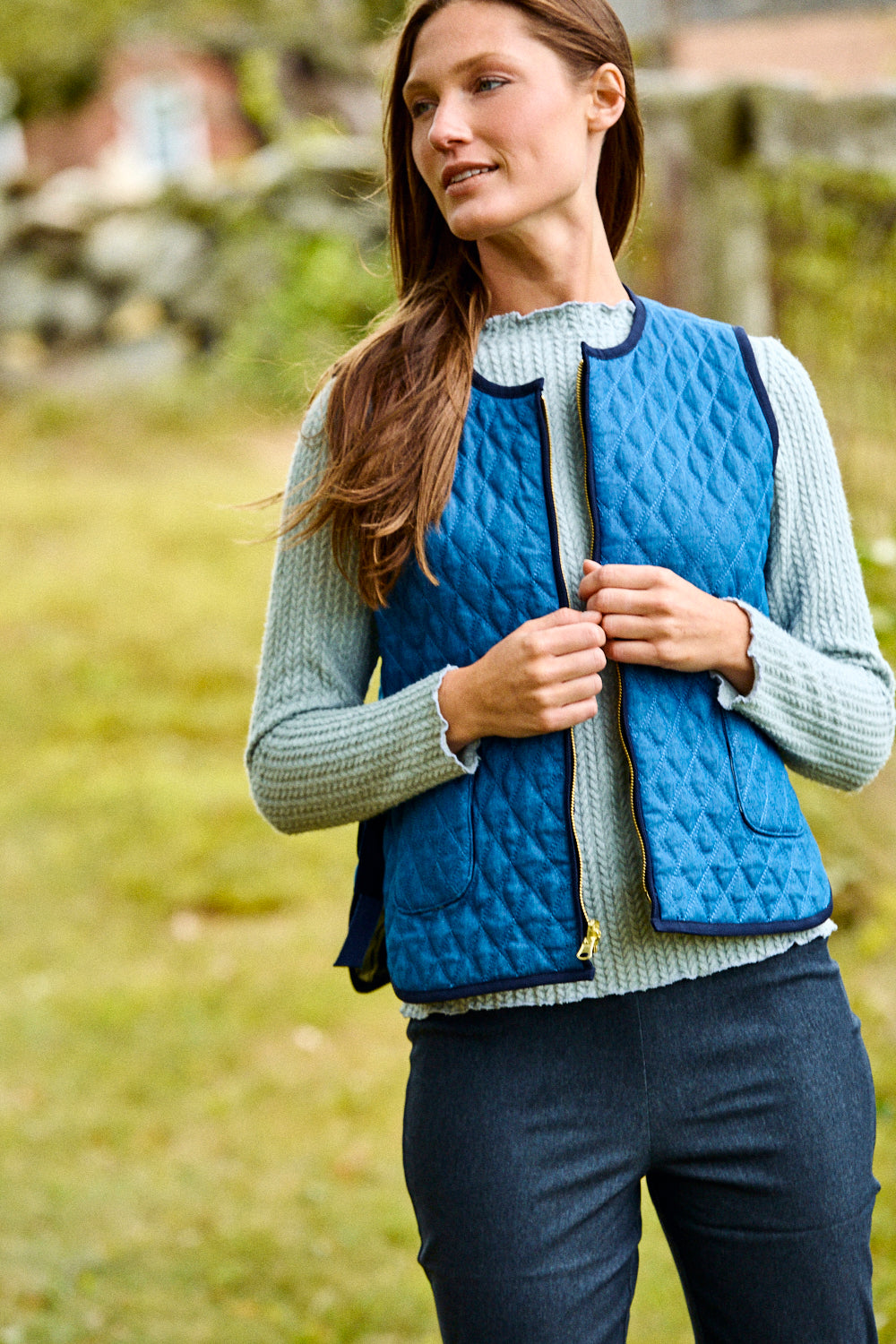 Woman wearing a blue quilted vest outdoors in a natural setting