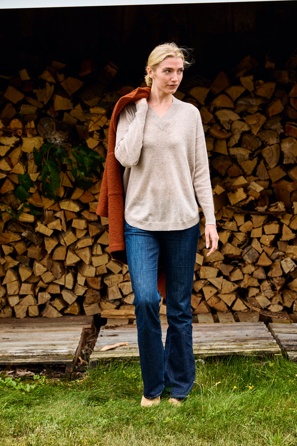 Woman standing in front of stacked firewood holding a red coat