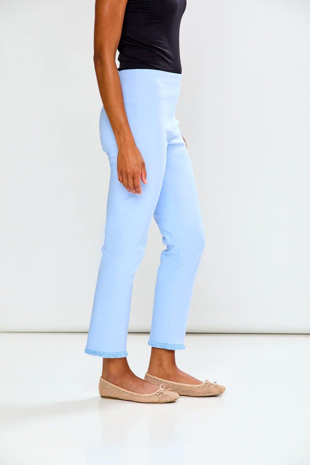 Person wearing light blue jeans and a black top on a white background