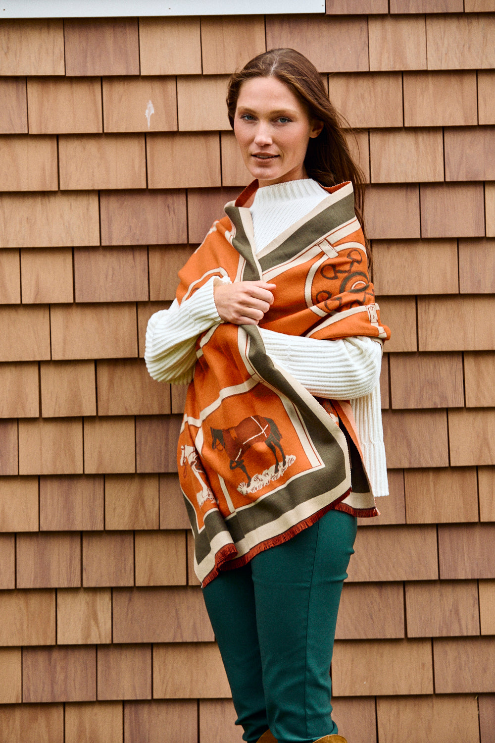 Woman wearing a patterned shawl against a wooden wall