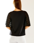 Woman in black top with butterfly sleeves