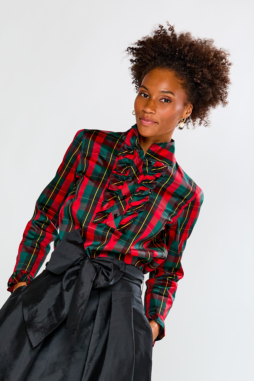Woman wearing a red and green plaid shirt with a black skirt on a white background