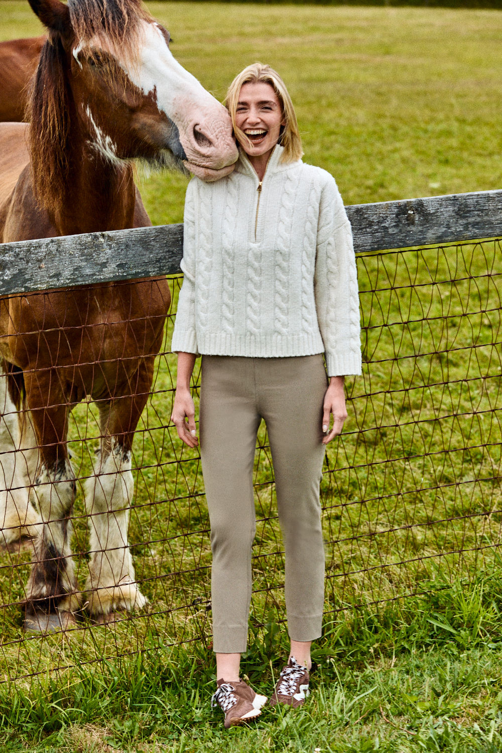 Woman standing next to a horse in a field