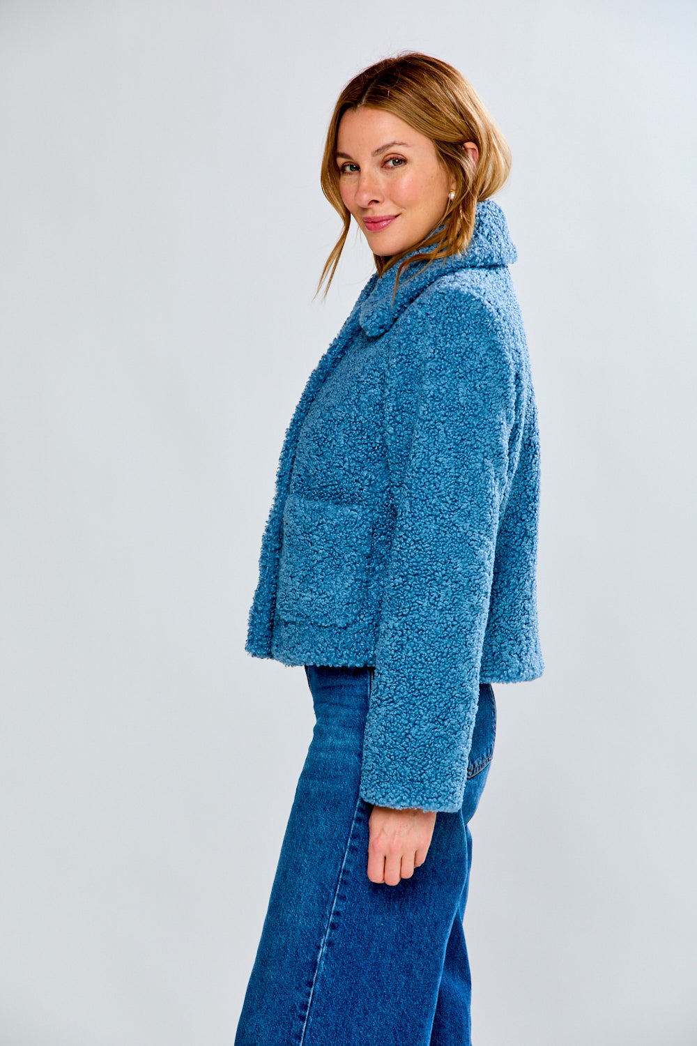 Woman wearing a blue fleece jacket and jeans on a white background