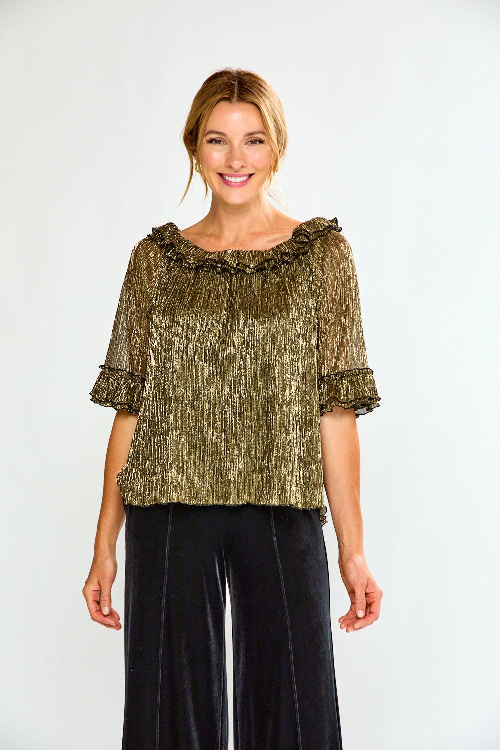 Woman wearing a gold off-shoulder top and black pants on a white background