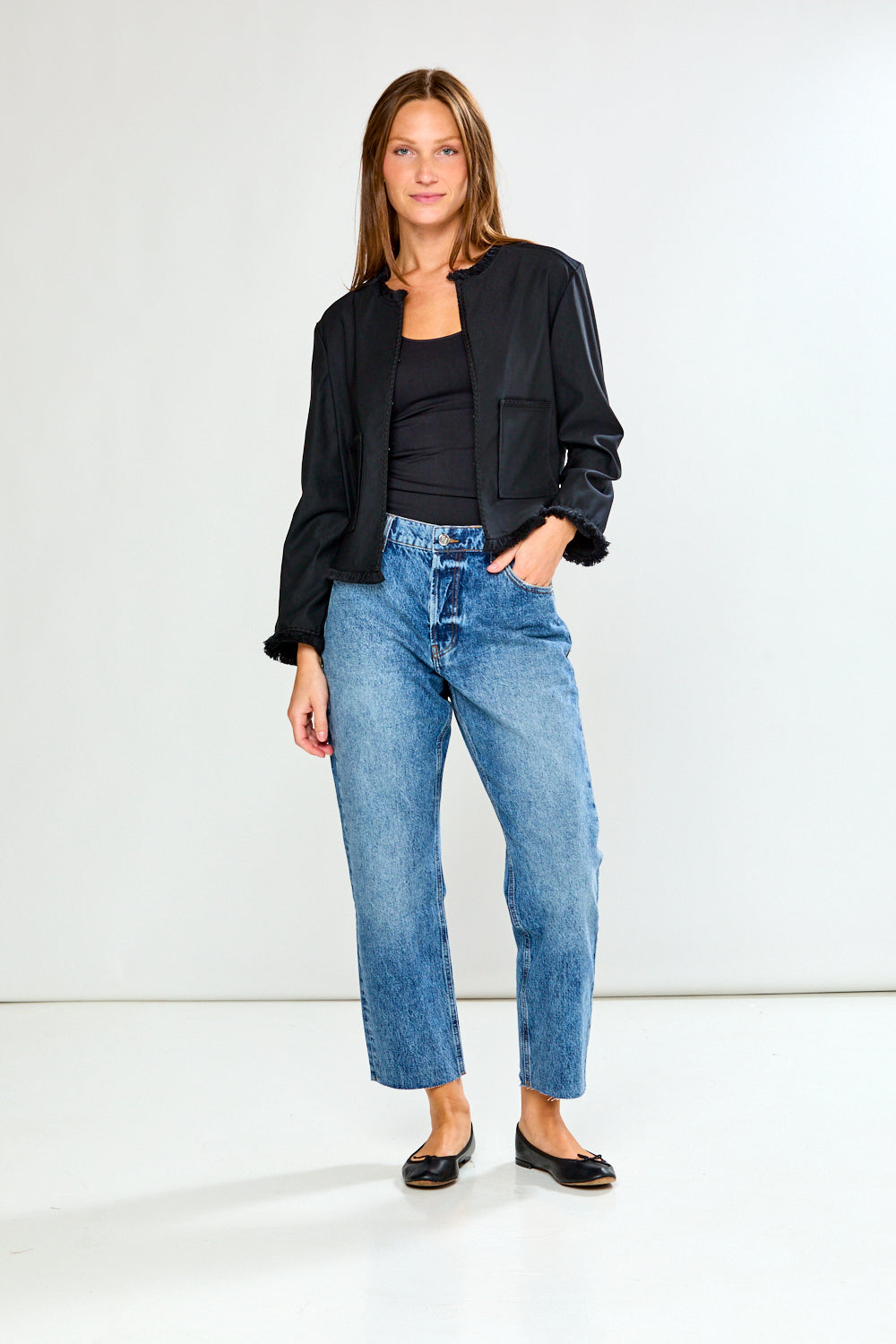 Woman wearing a black jacket and blue jeans on a white background