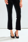 Black velvet pants worn by a person on a white background