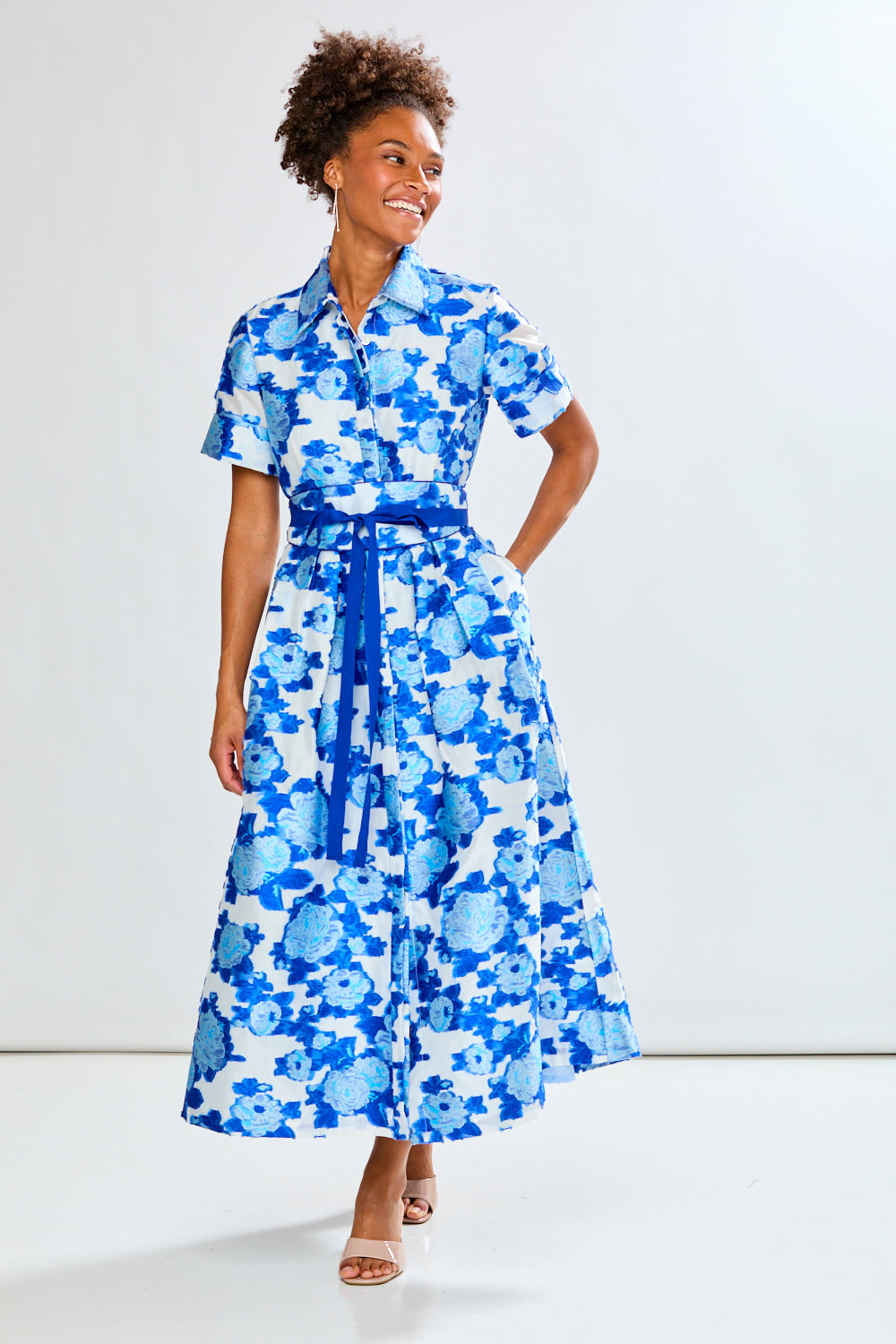 Woman wearing a blue floral dress against a white background
