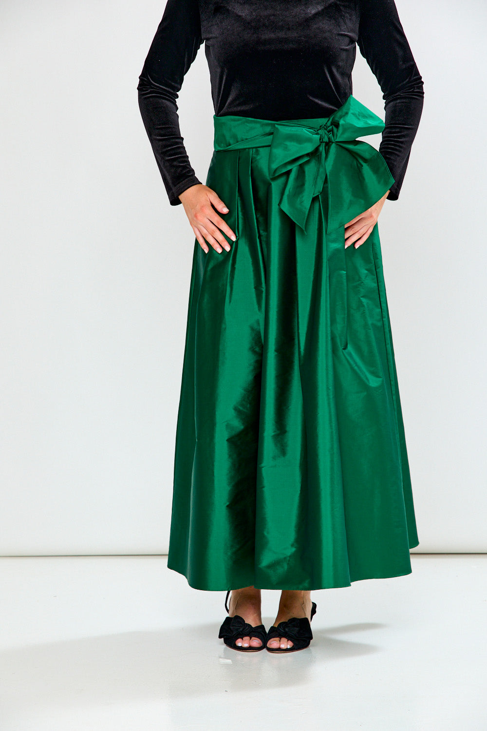 Woman wearing a Black top and Emerald skirt on a white background