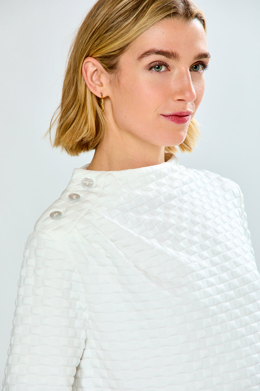 Woman wearing a white textured top against a light gray background