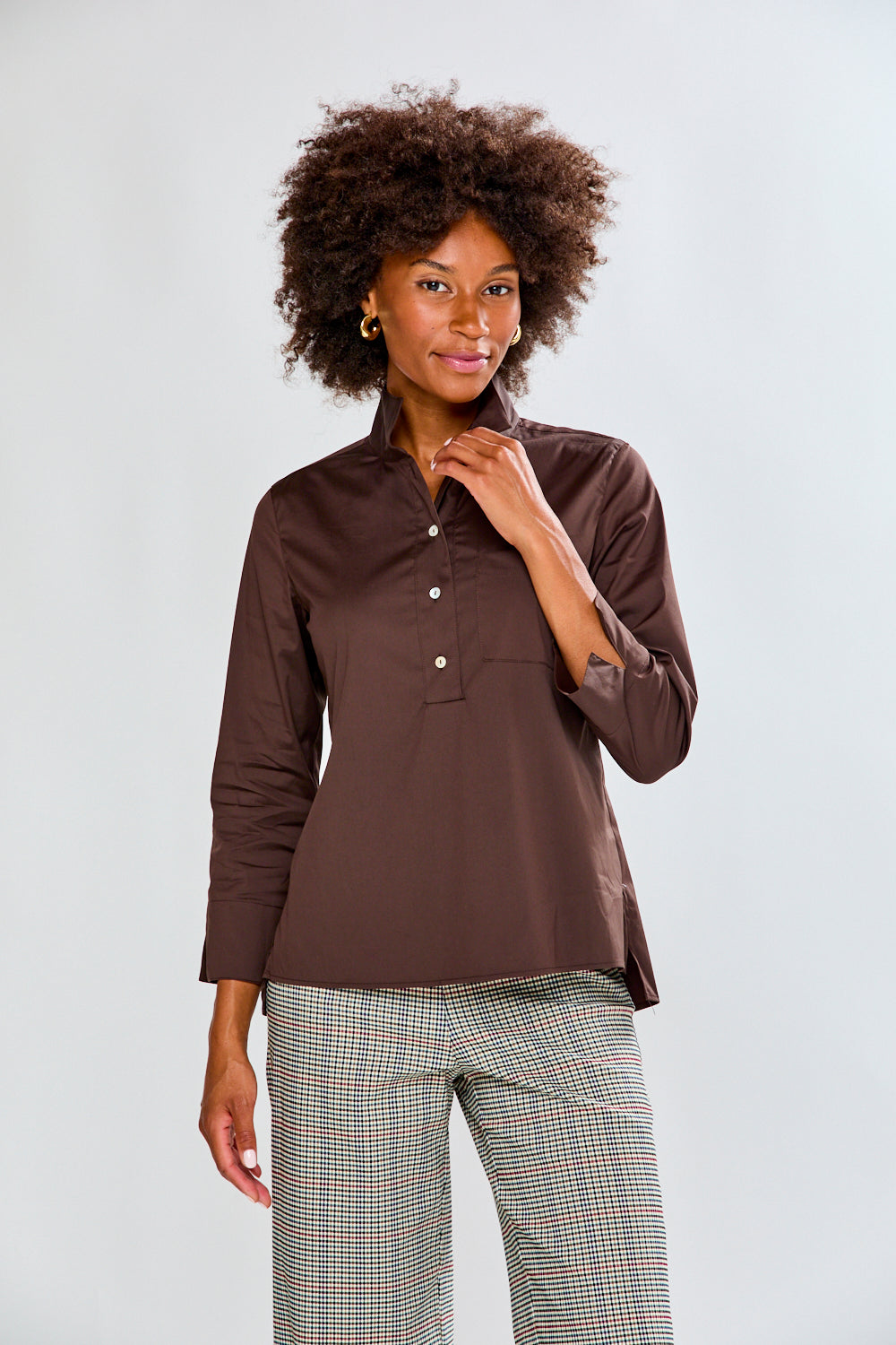 Woman wearing a chocolate shirt and plaid pants on a white background