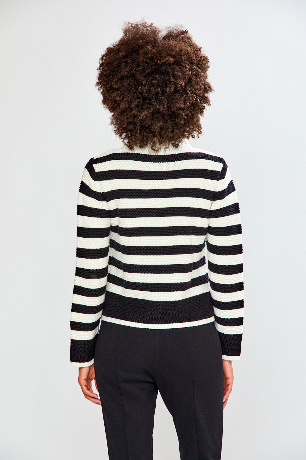 Person wearing a black and white striped sweater on a plain background