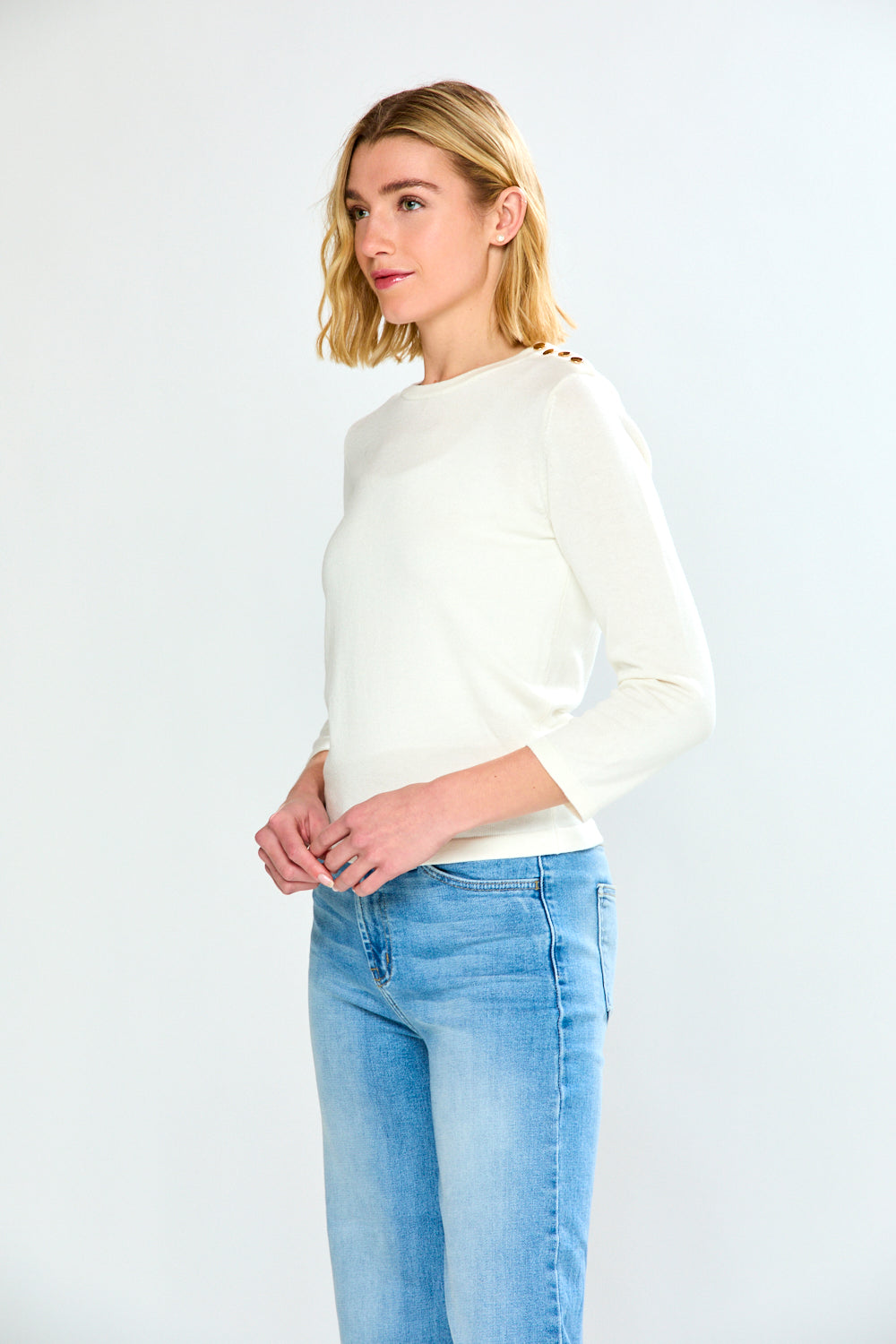Woman wearing a white sweater and light blue jeans on a white background