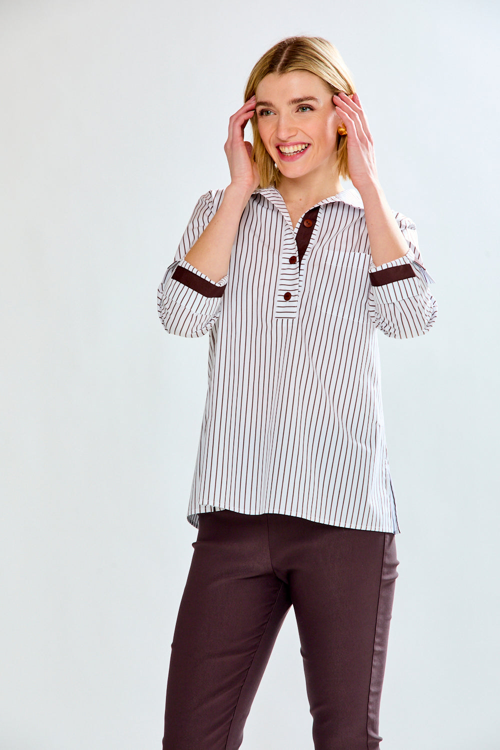 Woman wearing a striped shirt with brown accents on a white background
