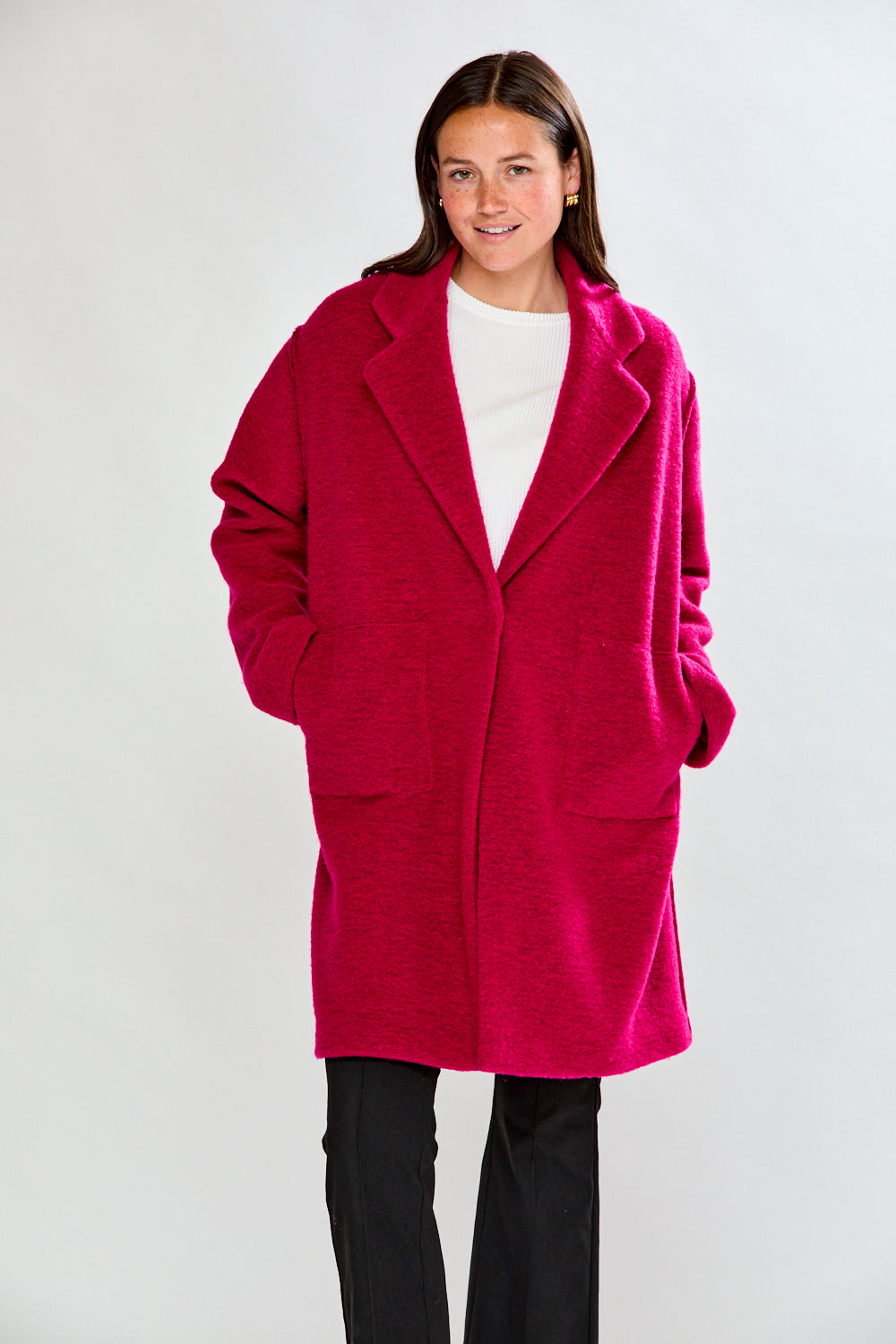 Woman wearing a bright pink coat against a white background