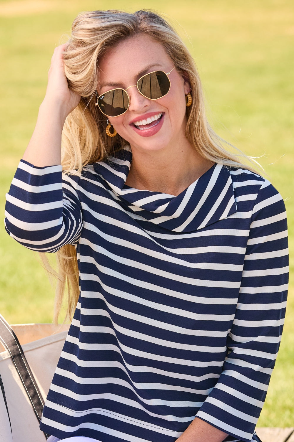Woman wearing a blue and white striped dress with sunglasses, standing outdoors.
