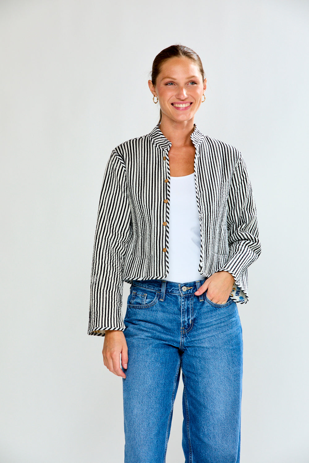 Woman wearing a striped shirt and blue jeans against a white background