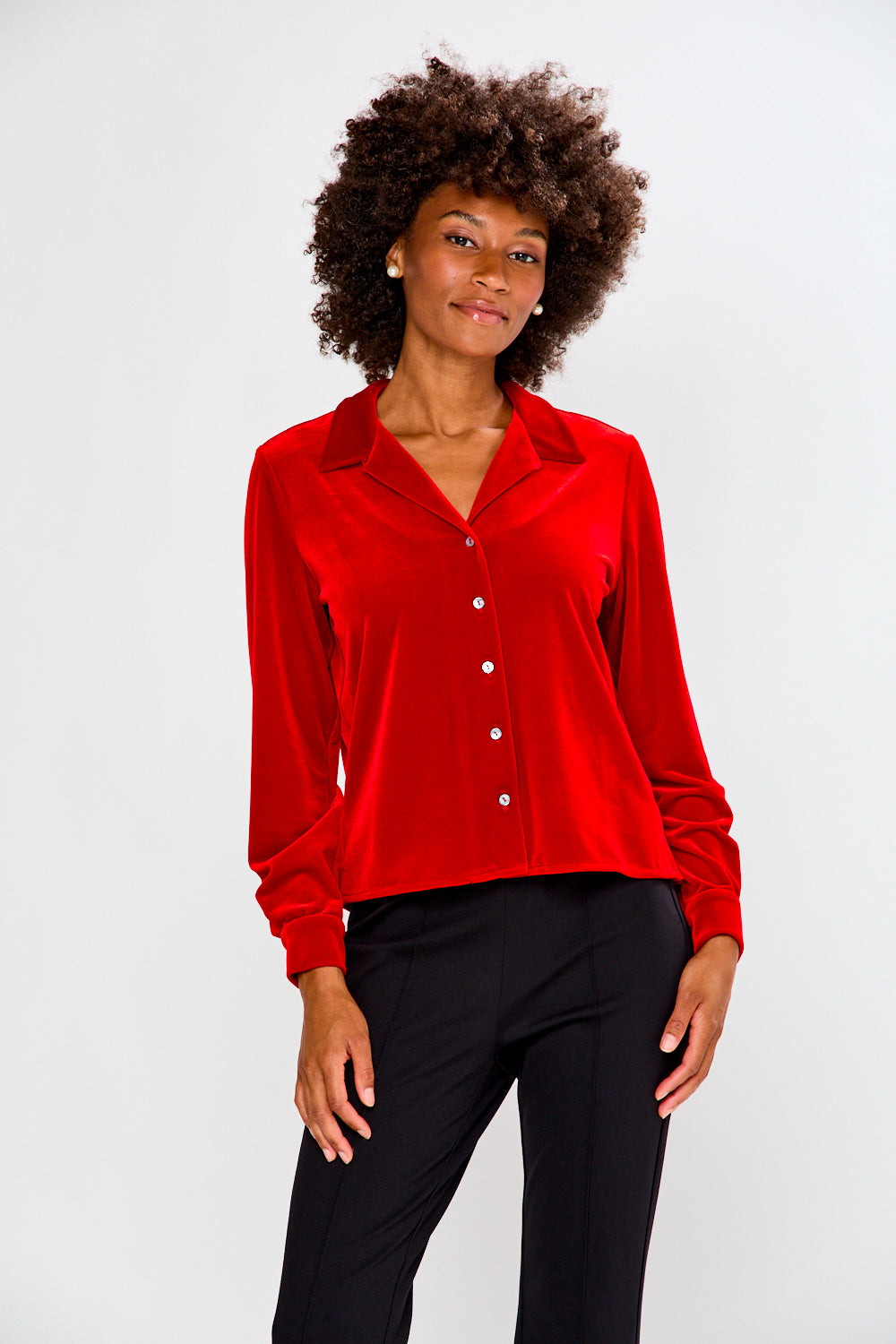 Woman wearing a red velvet shirt and black pants on a white background