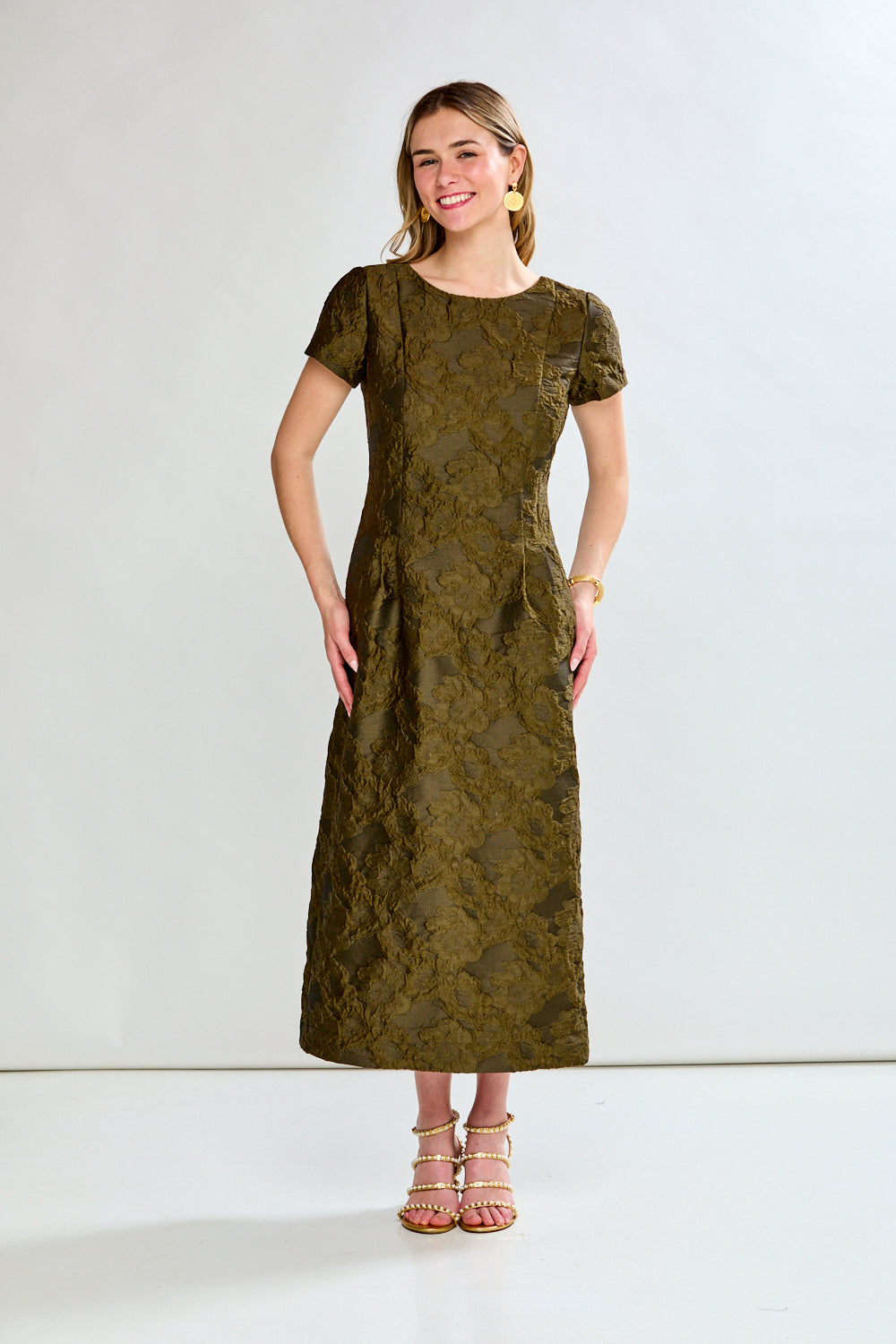 Woman wearing a green dress with a subtle pattern on a white background
