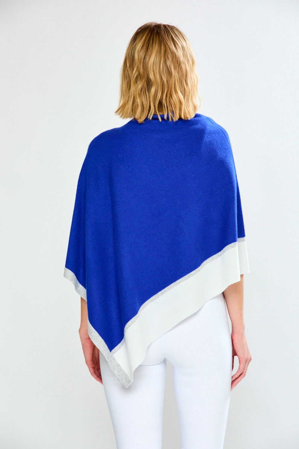 Woman wearing a blue and white poncho against a white background