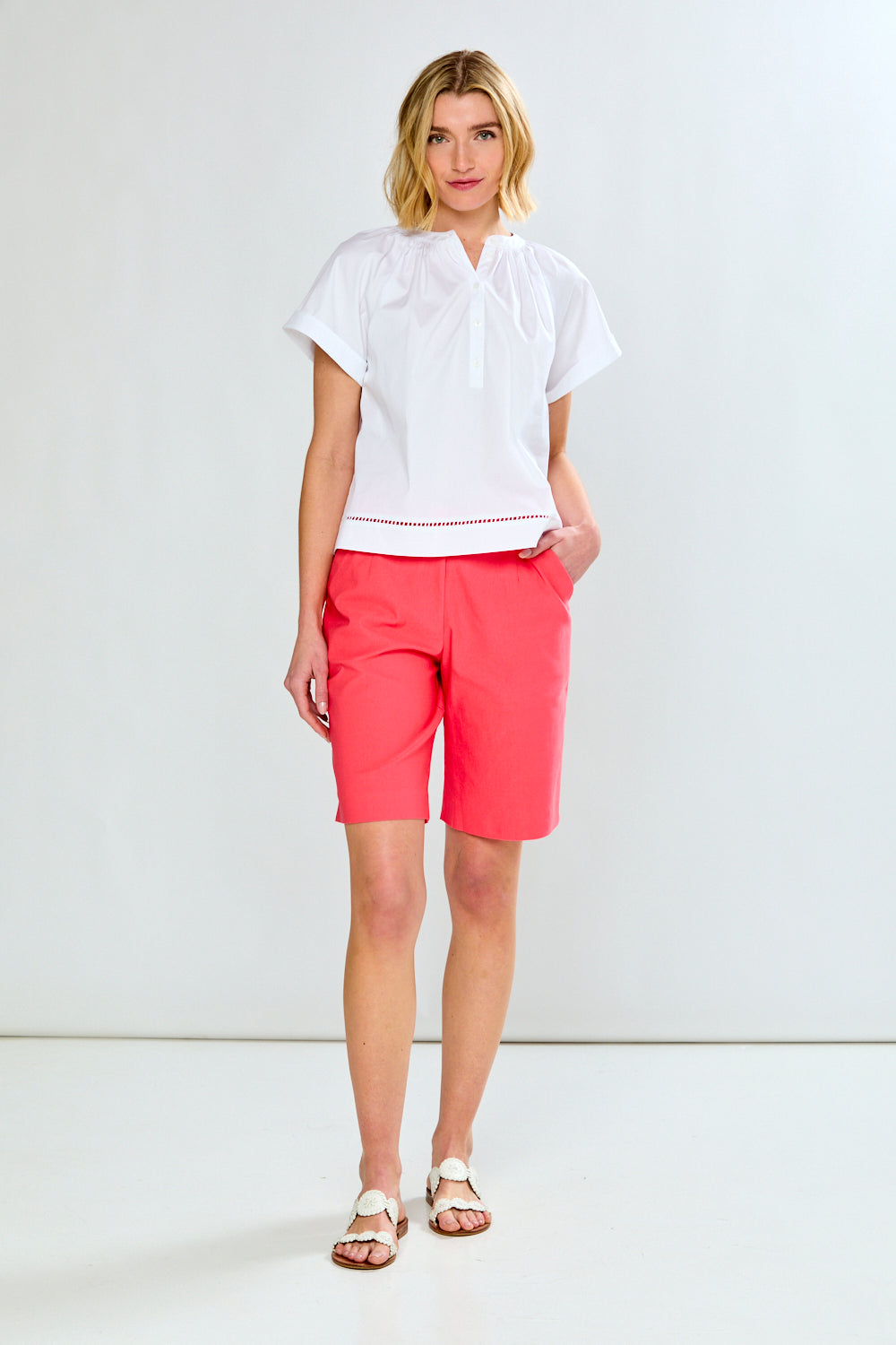 Woman wearing a white blouse and pink shorts on a white background