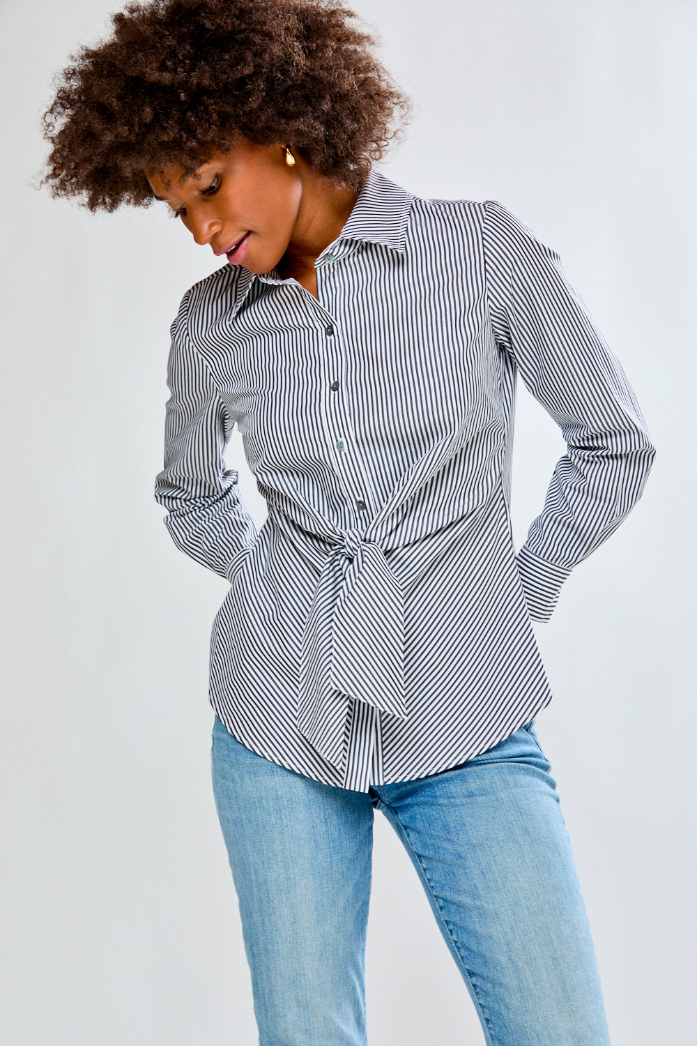 Woman wearing a striped shirt and jeans on a plain background
