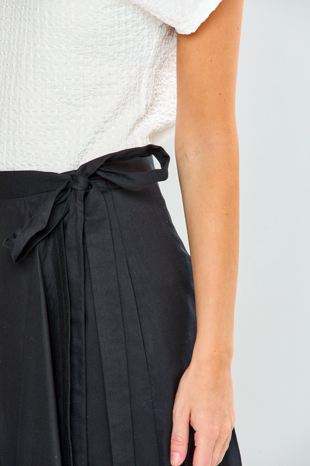 Black wrap skirt with a white top on a plain background