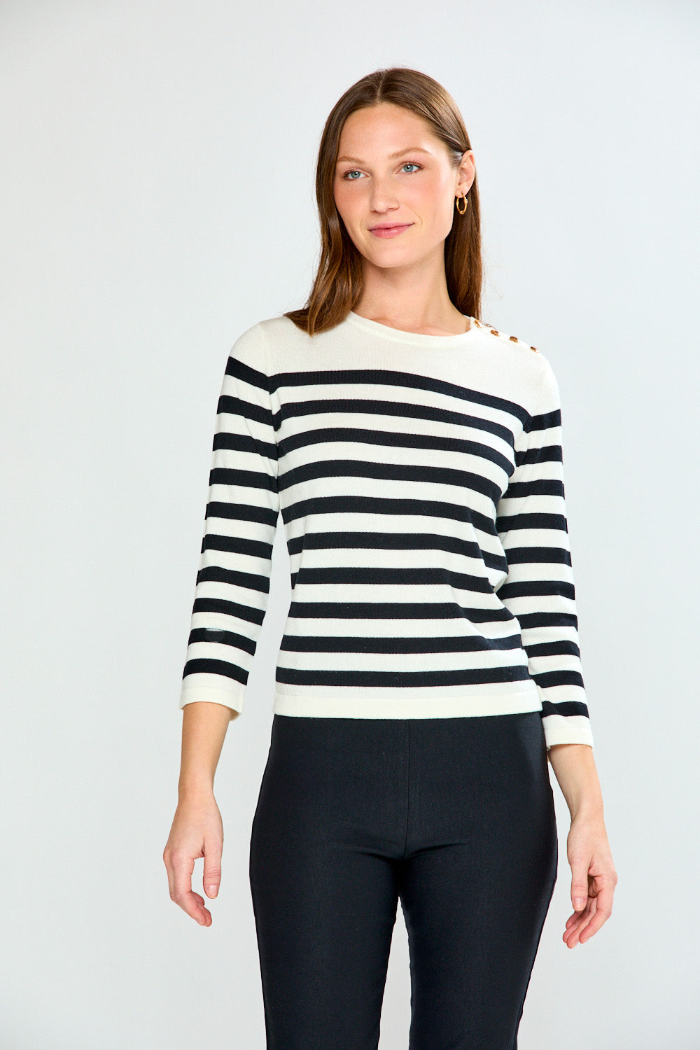 Woman wearing a black and white striped sweater against a plain background