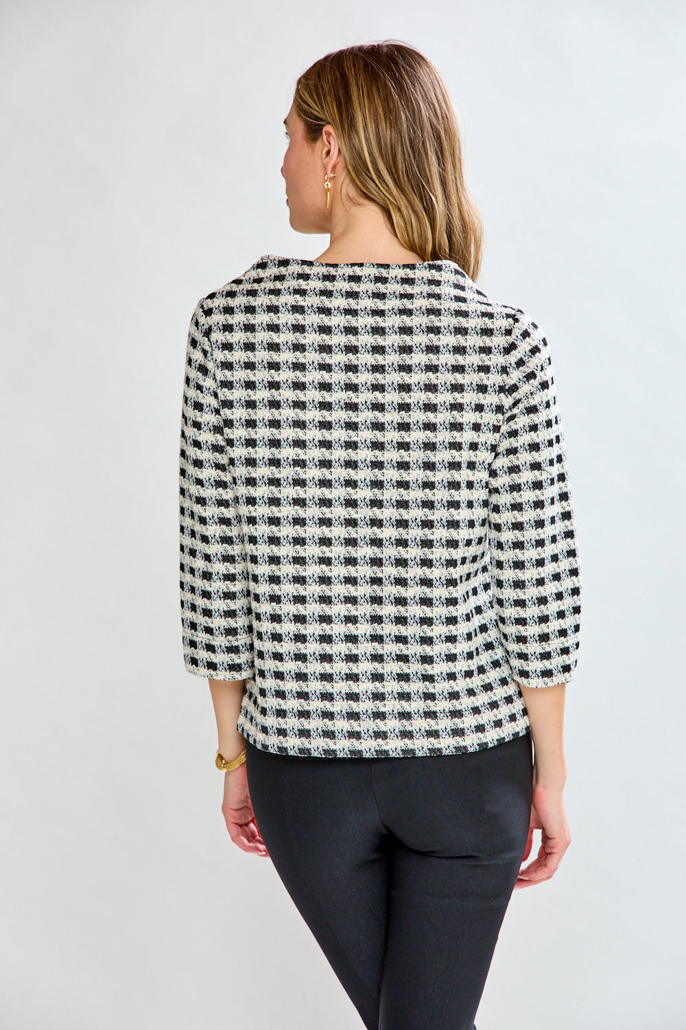 Woman wearing a black and white checkered blouse against a plain background