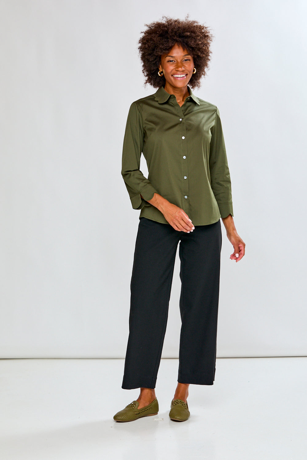Woman wearing a green shirt and black pants against a white background