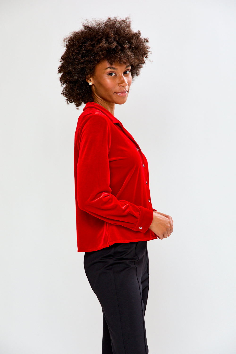 Woman wearing a red blouse and black pants against a white background
