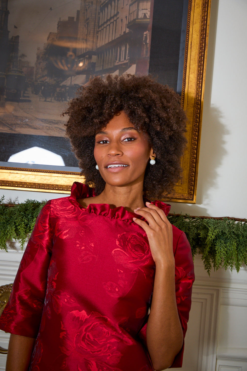 woman in front of fireplace with holly behind her