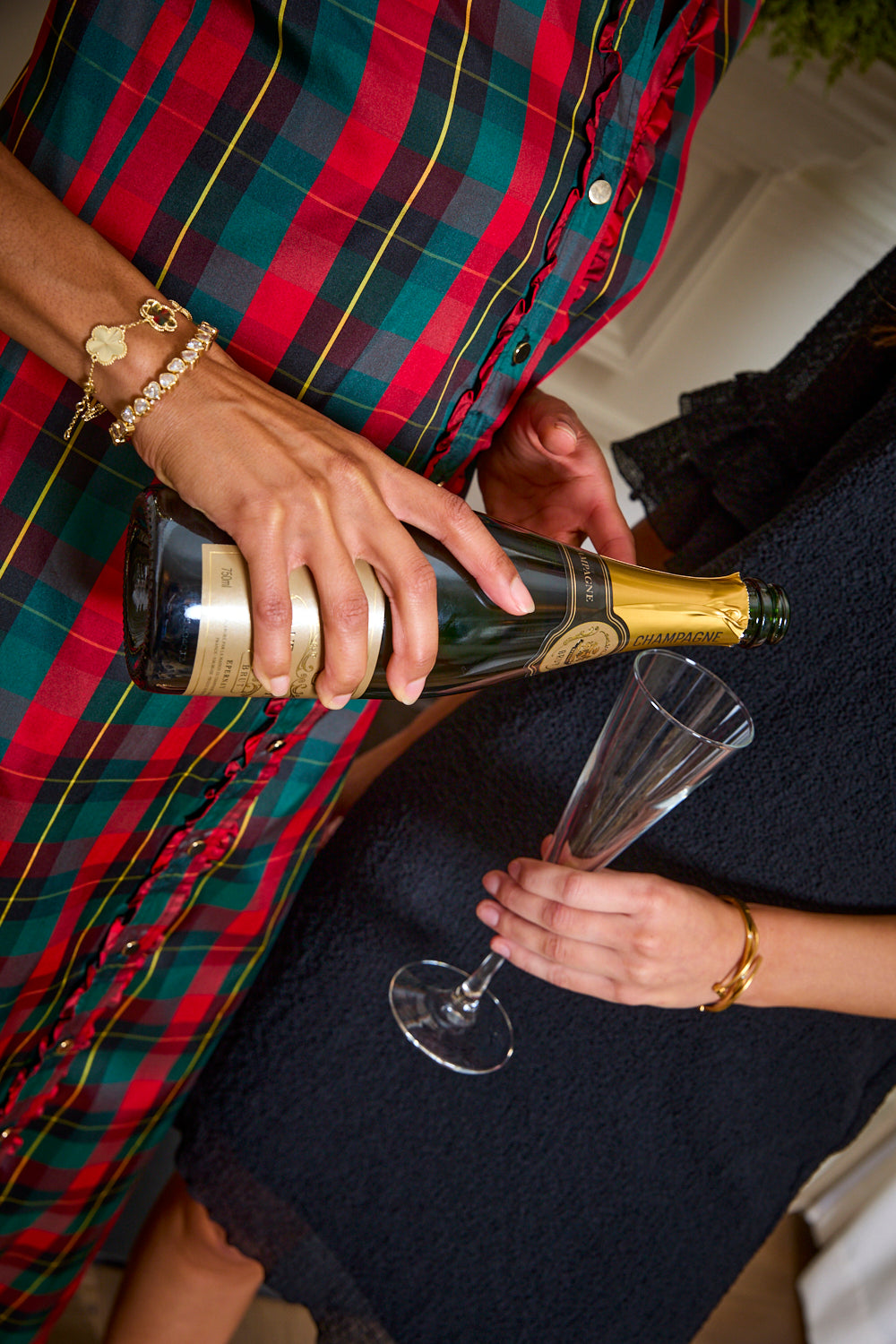 Person pouring champagne from a bottle into a glass with a focus on the action.