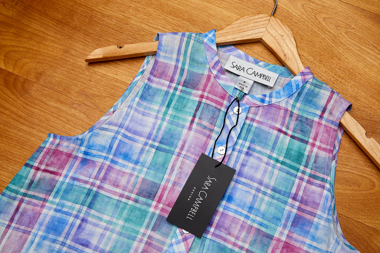 A madras blouse on a hanger with the Sara Campbell tag showing.