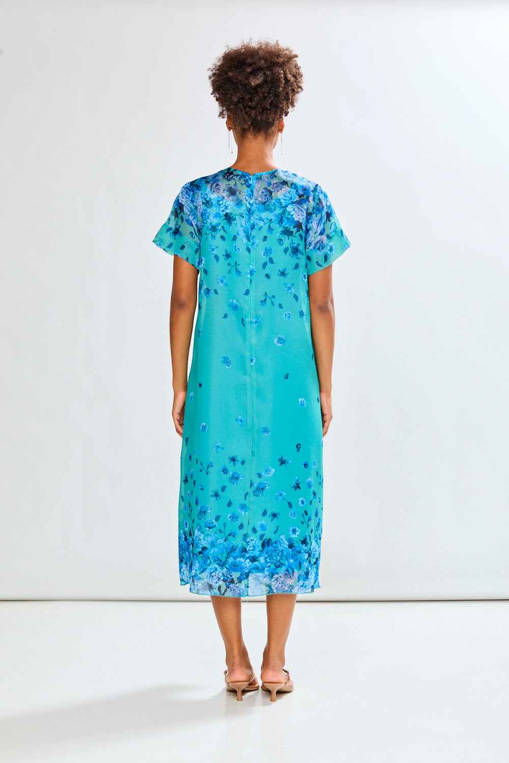 Woman wearing a blue floral dress against a white background