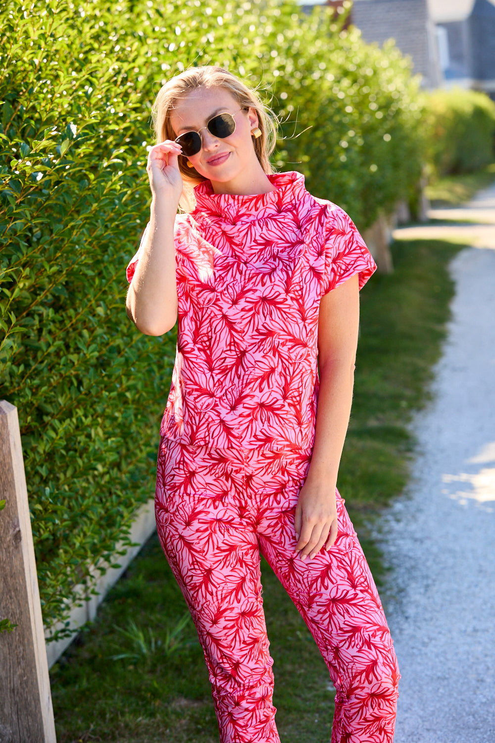 Woman wearing a pink and red patterned outfit standing outdoors.