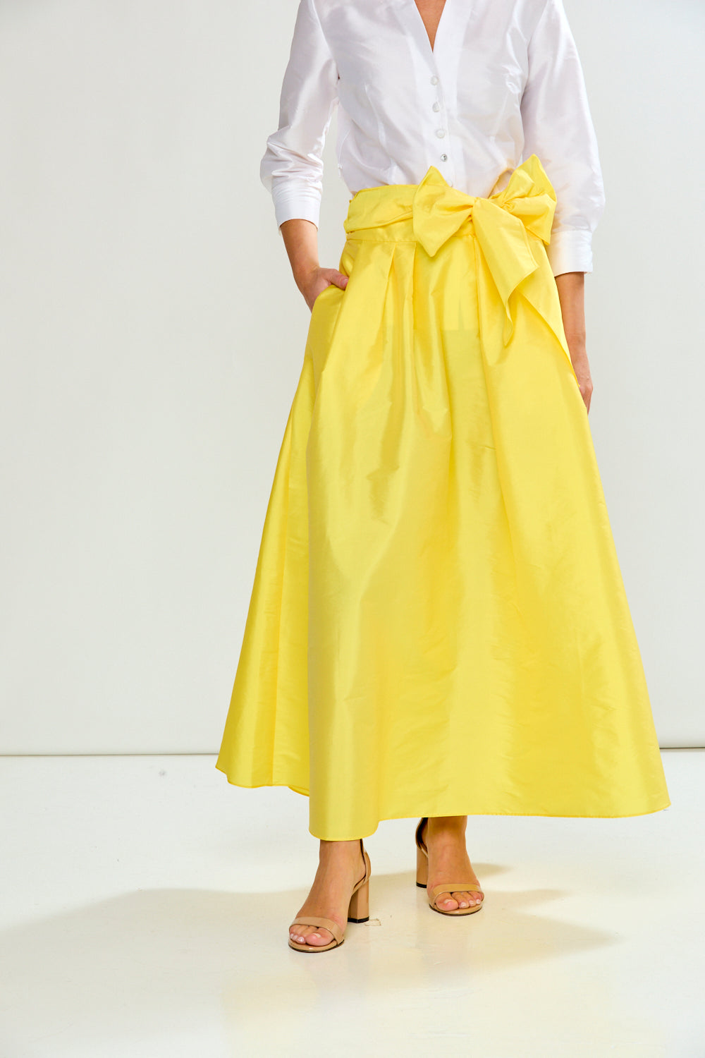 Person wearing a white shirt and yellow skirt with a bow on a white background
