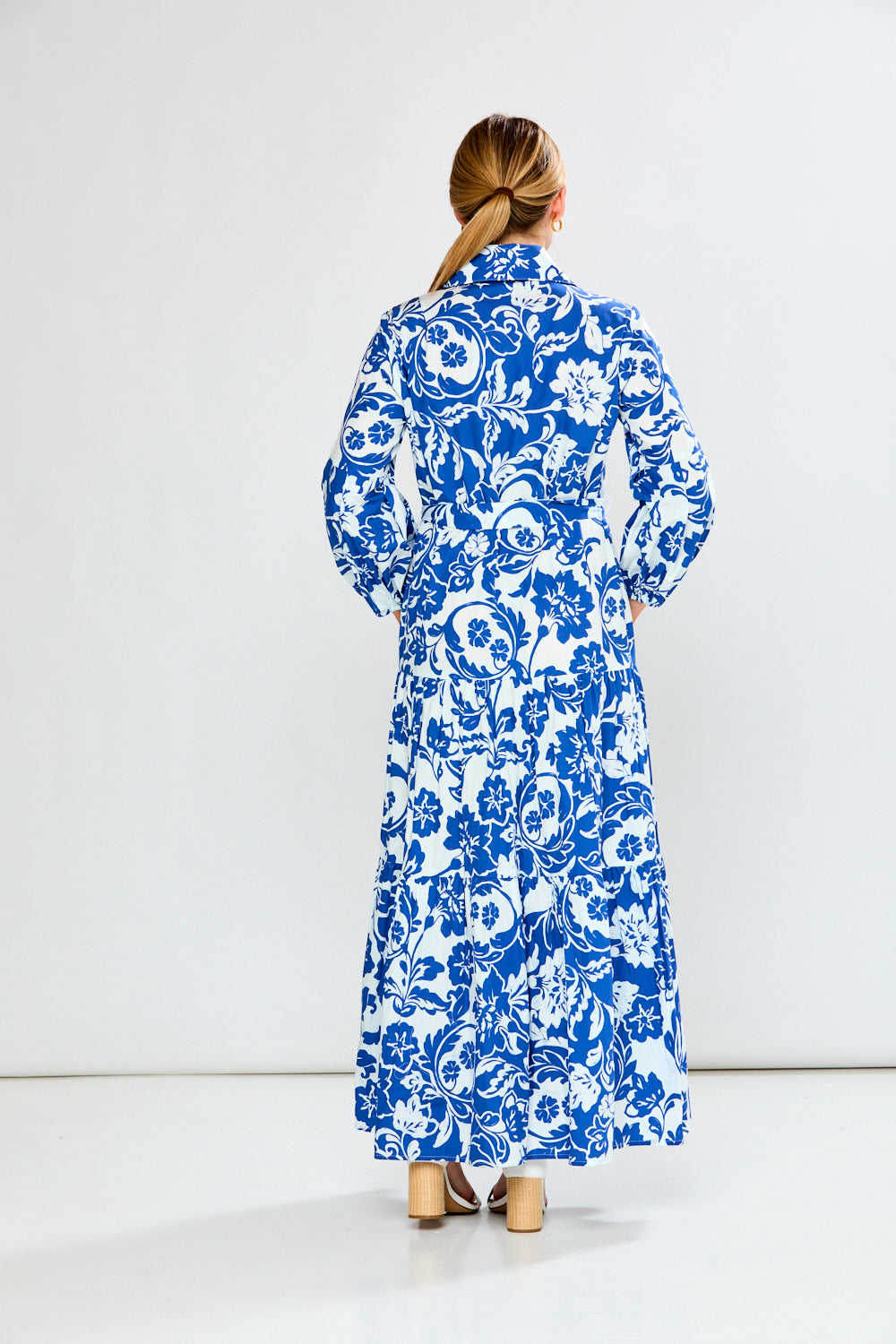 Woman wearing a blue and white floral dress against a white background