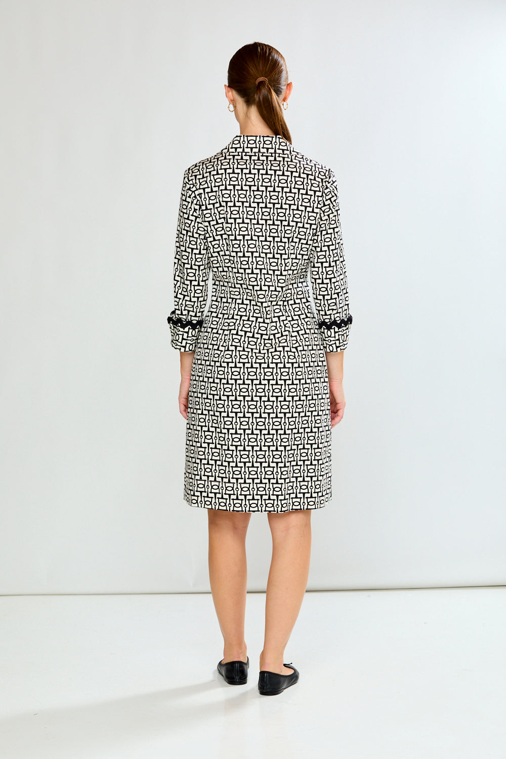 Woman wearing a black and white patterned dress on a white background