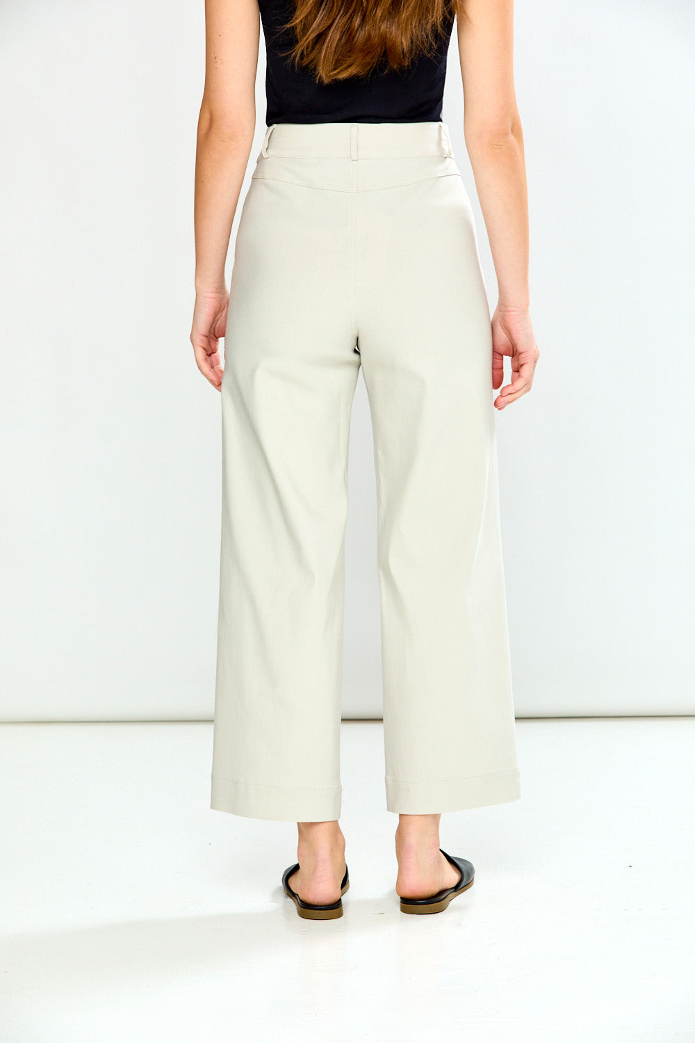 Person wearing stone wide-leg pants and black sandals on a white background