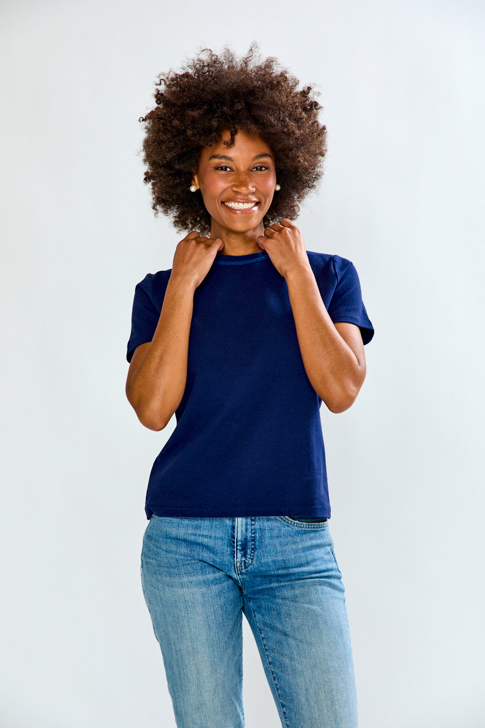Woman wearing a blue shirt and jeans against a white background