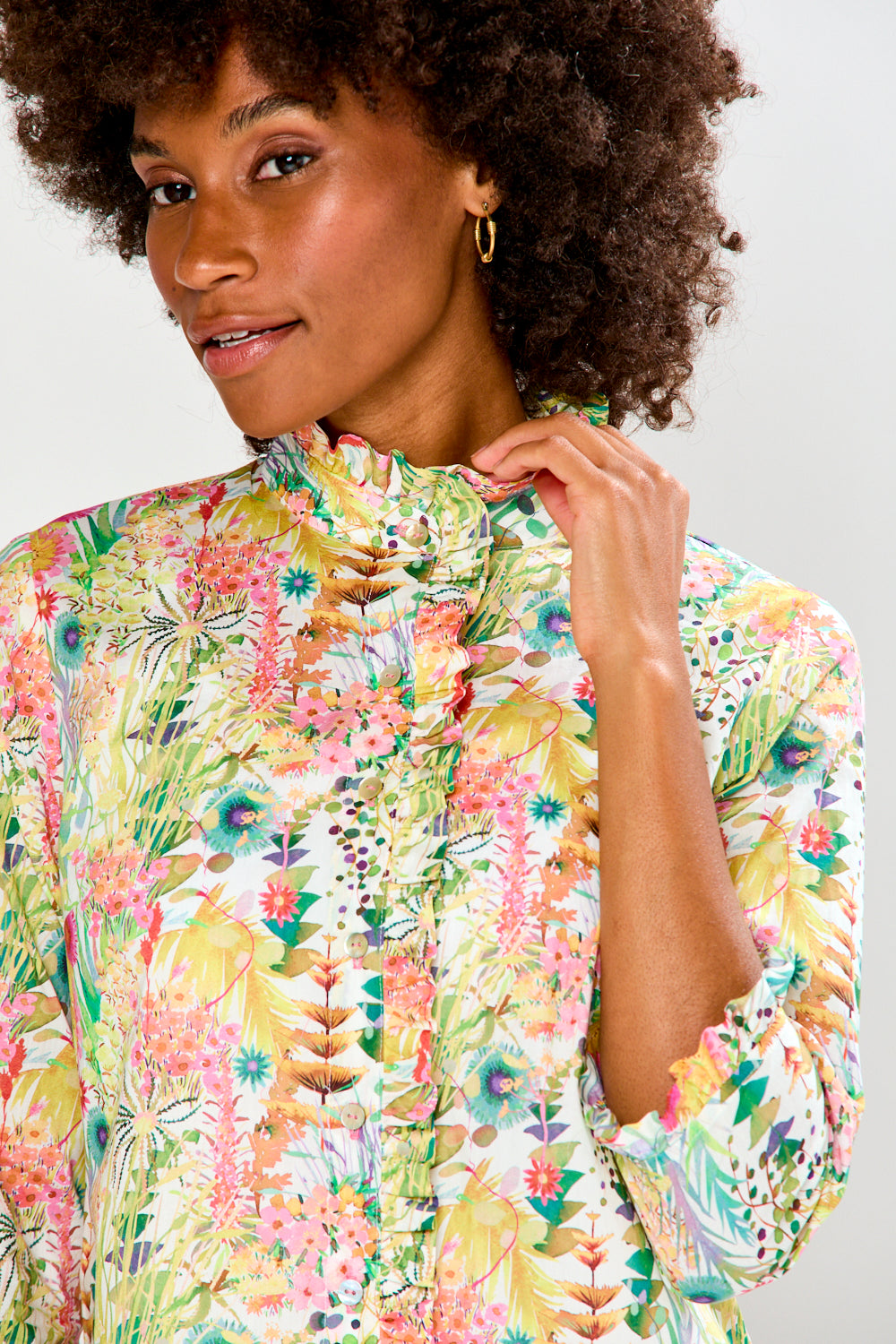 Woman wearing a colorful floral dress against a plain background