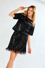 Woman wearing a black sequin dress against a white background