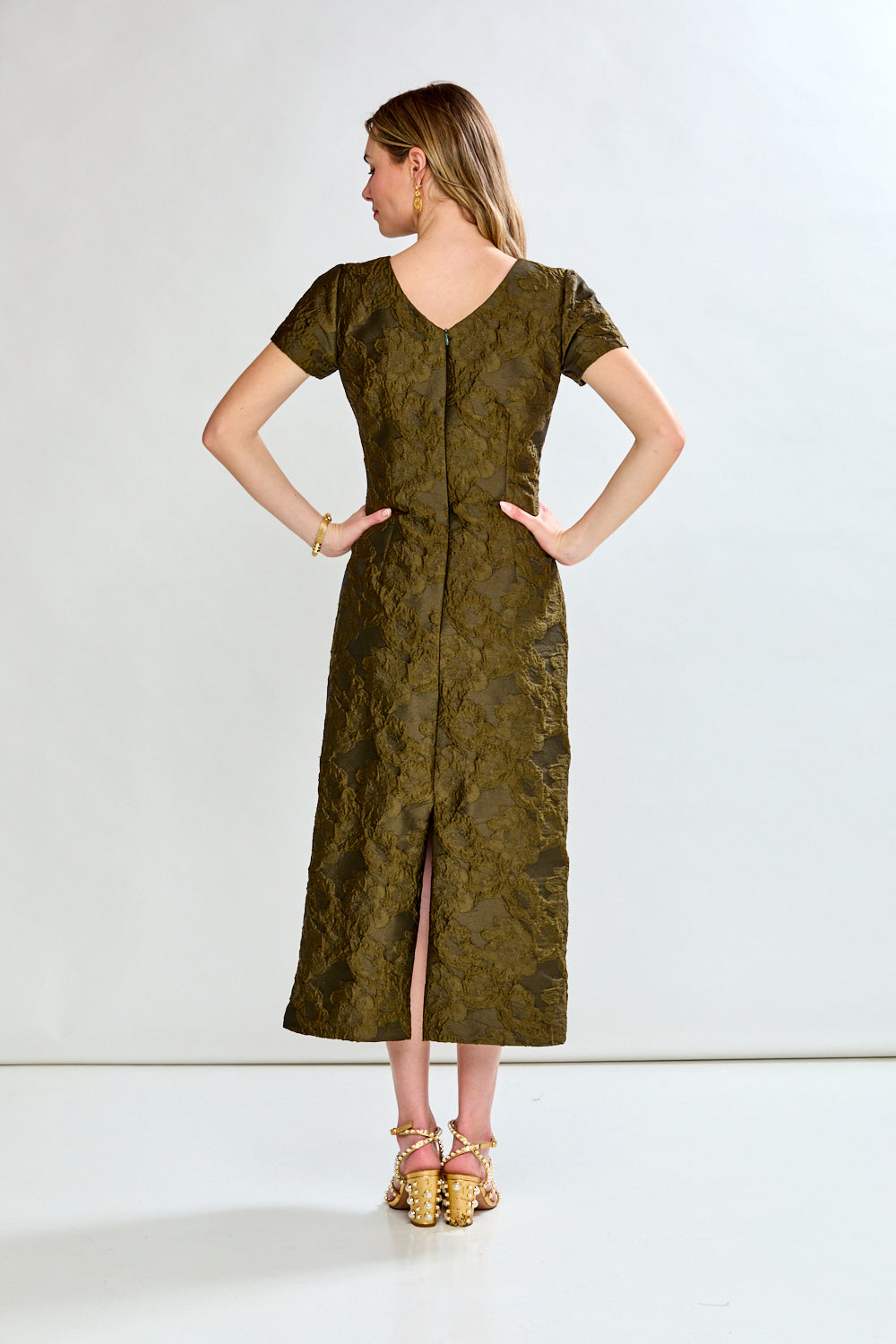 Woman wearing a green dress with a subtle pattern on a white background
