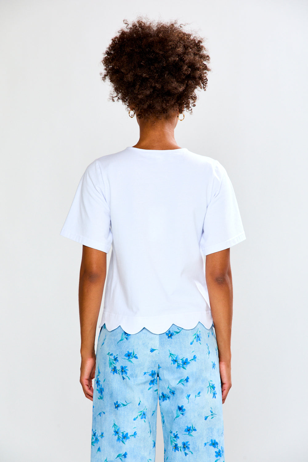 Person wearing a white t-shirt and blue floral pants on a plain background