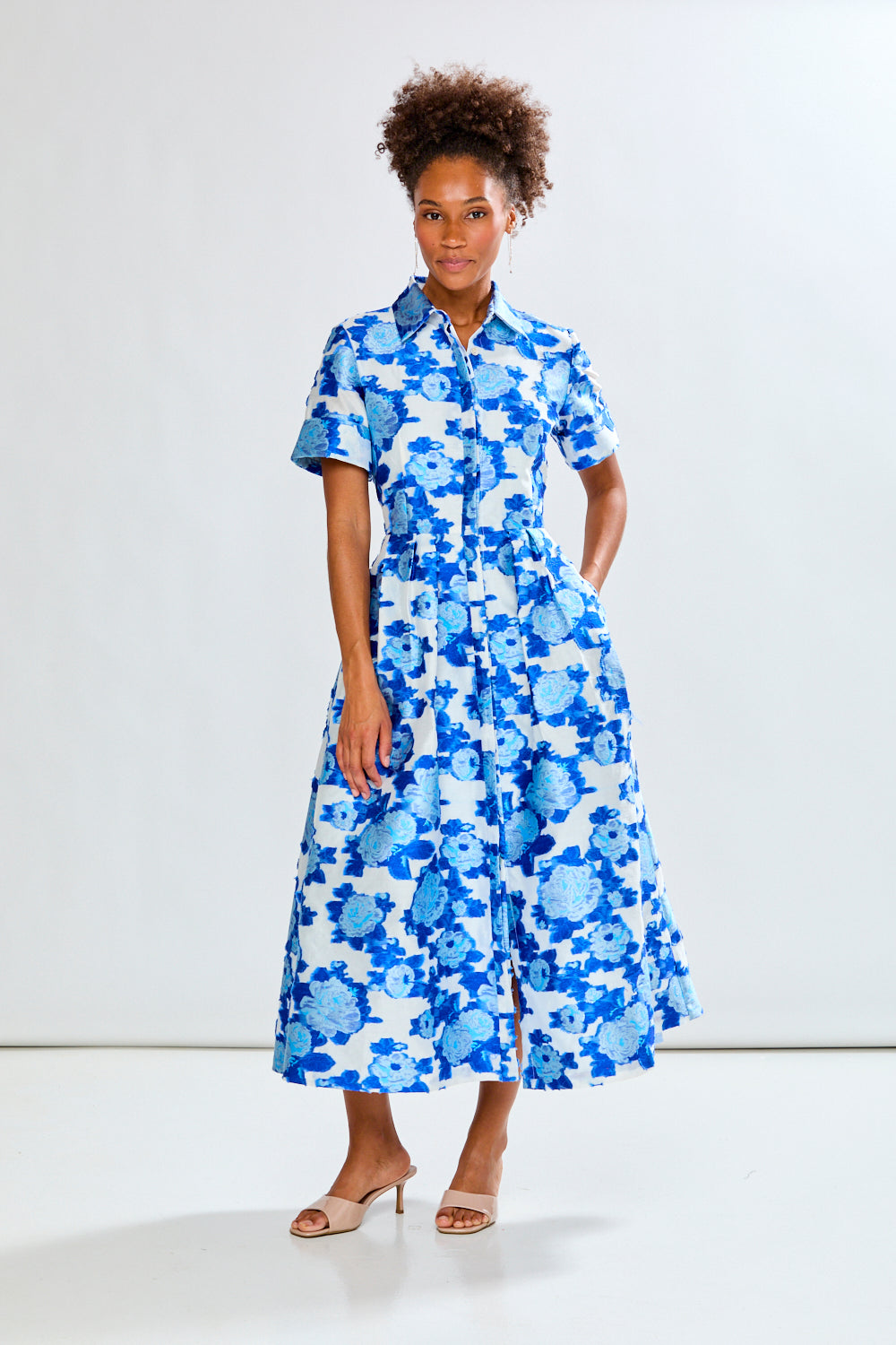 Woman wearing a blue floral dress against a white background